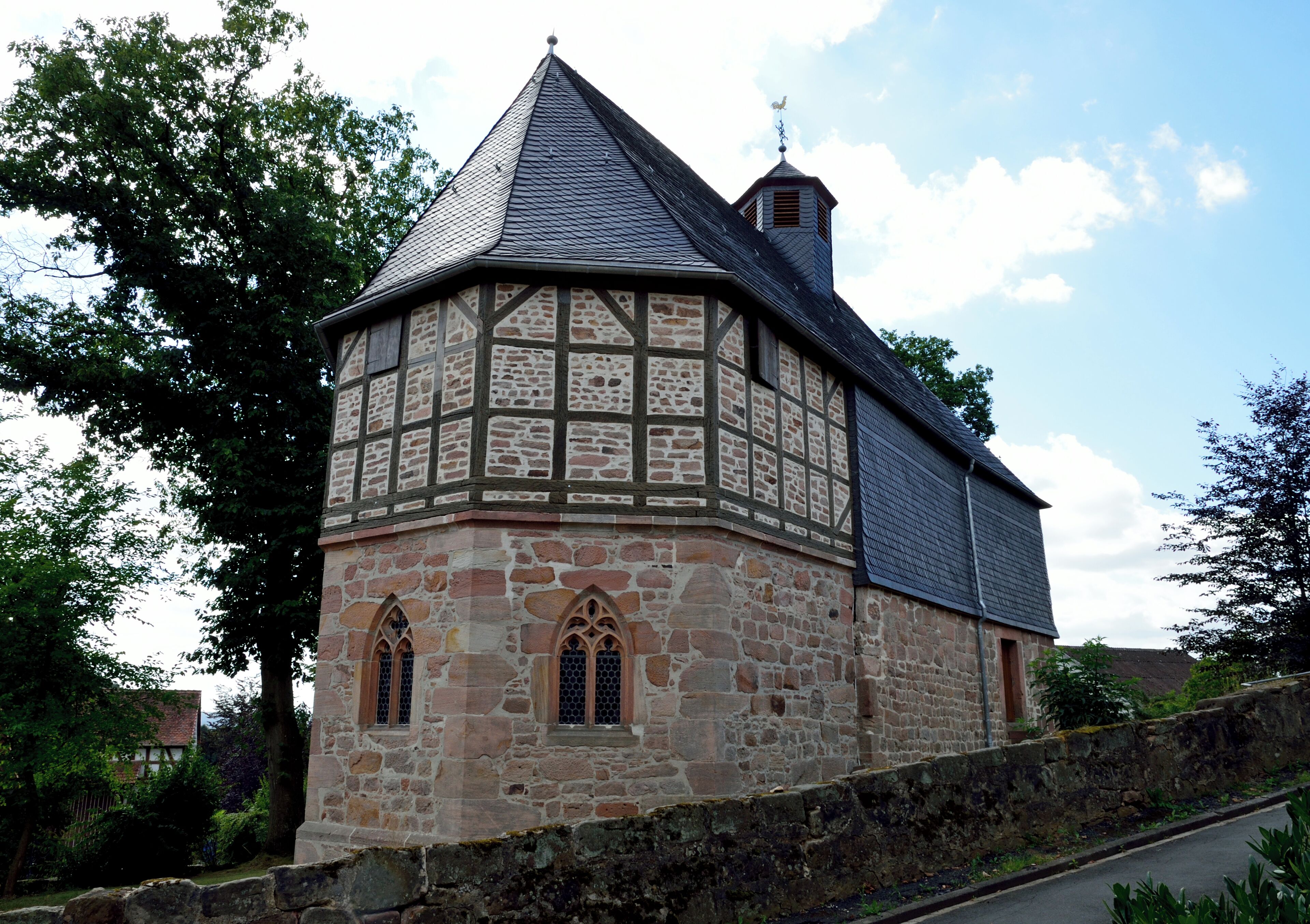 A historic stone building with a steeply pitched roof and a small tower.