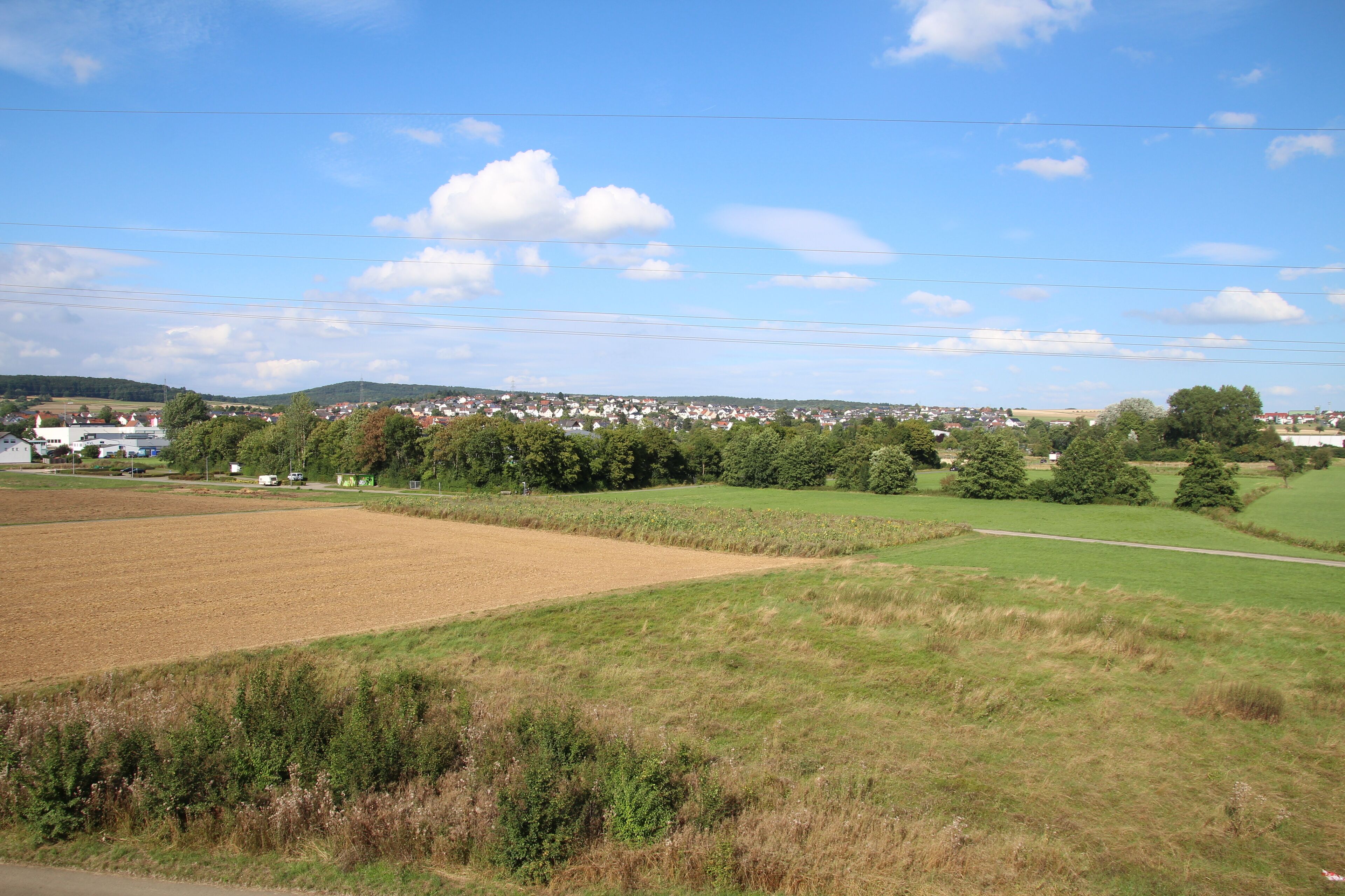 A rural landscape with fields, trees, and a distant village.