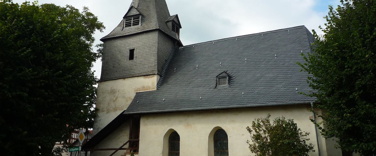 A church with a tall steeple and a grey roof.
