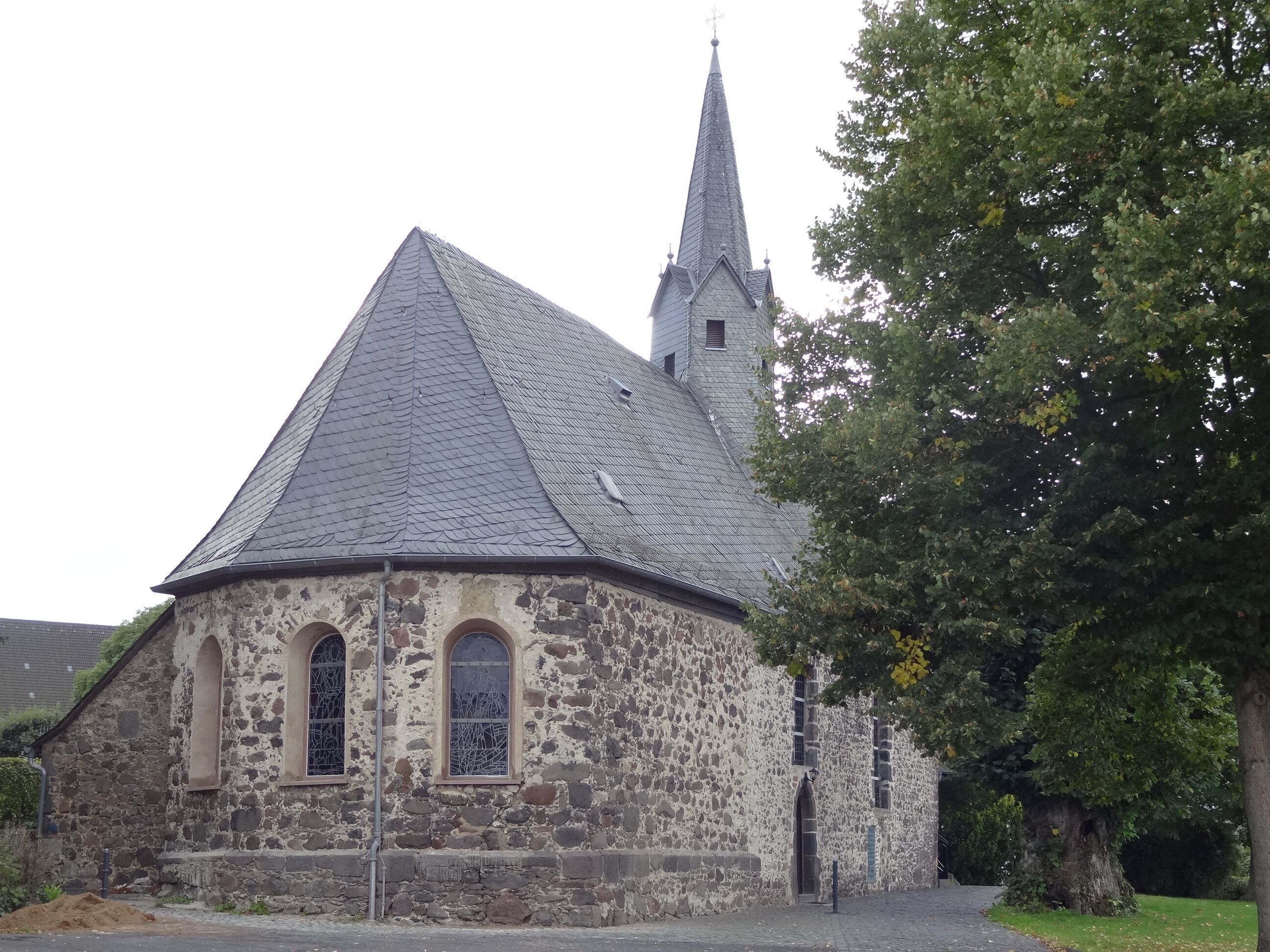 A stone church with a pointed steeple and arched windows.