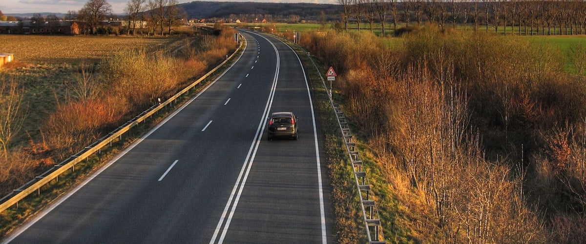 A highway curving through a rural landscape with fields and trees.