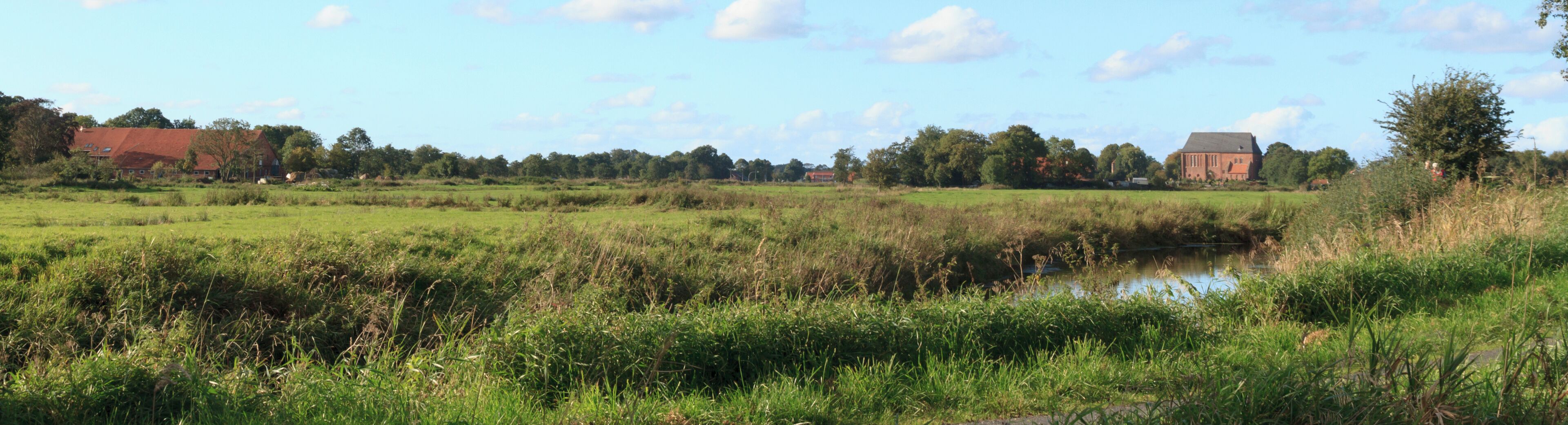 A rural landscape with a river, fields, and a church.