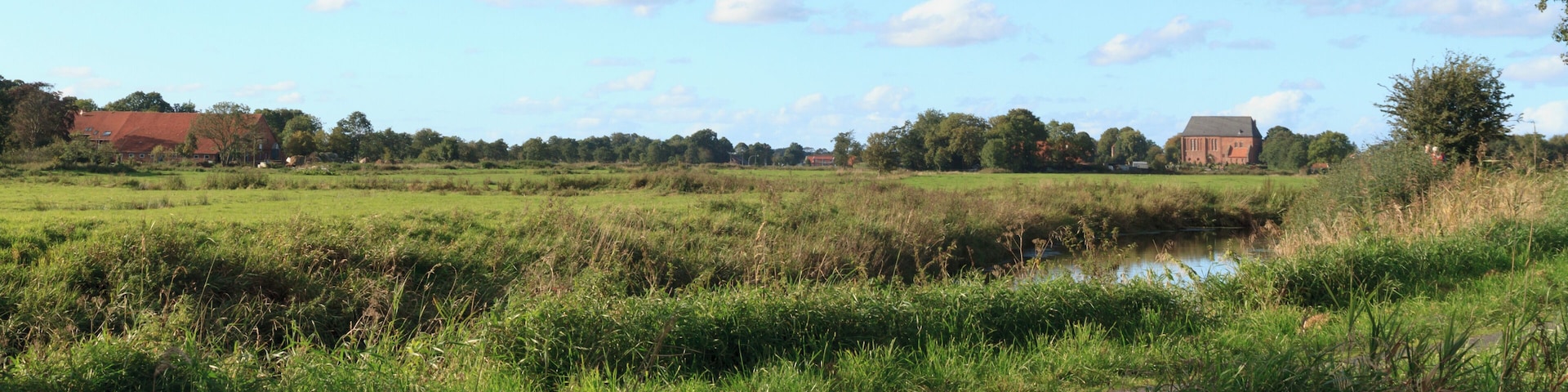 A rural landscape with a river, fields, and a church.