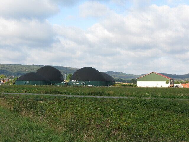 A rural landscape with two large greenhouses and a smaller building.