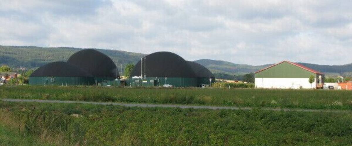 A rural landscape with two large greenhouses and a smaller building.