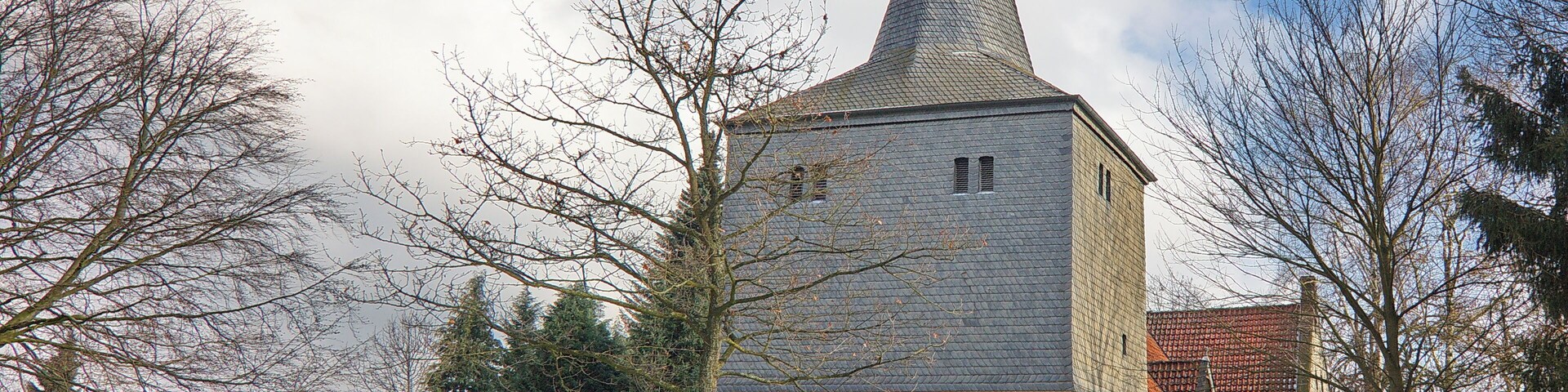 A church with a tall steeple and a red-tiled roof.