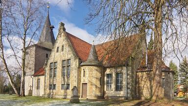 A historic stone church with a red-tiled roof and a tall steeple.
