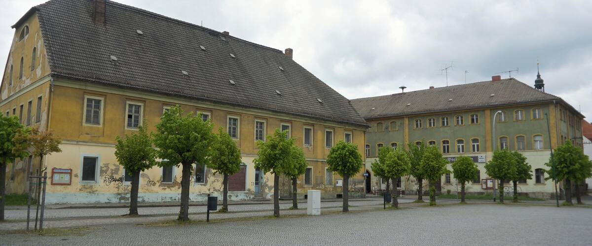 A historic building with a tiled roof and a courtyard with trees.