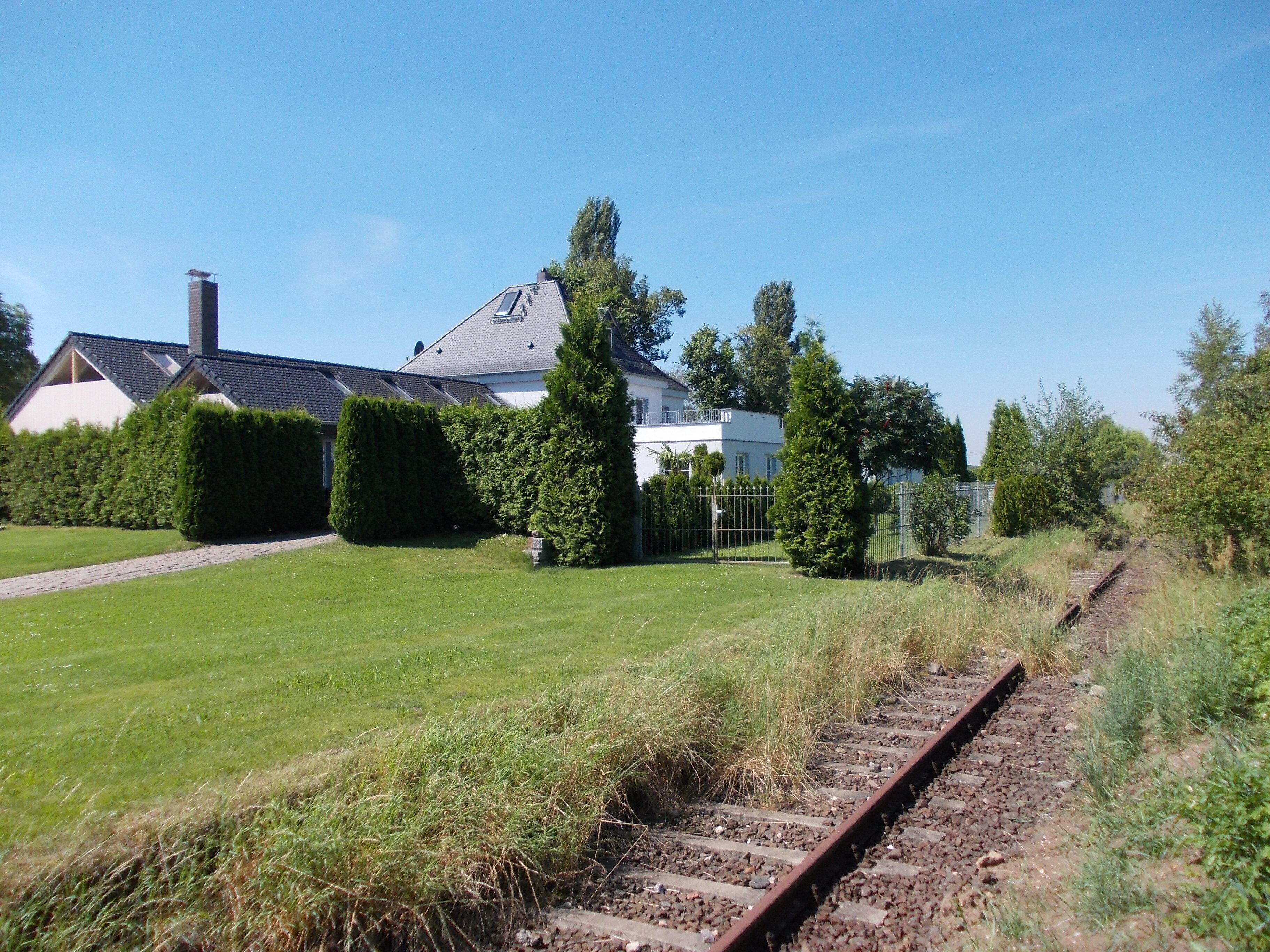 A residential area with a house, a lawn, and a railway track.