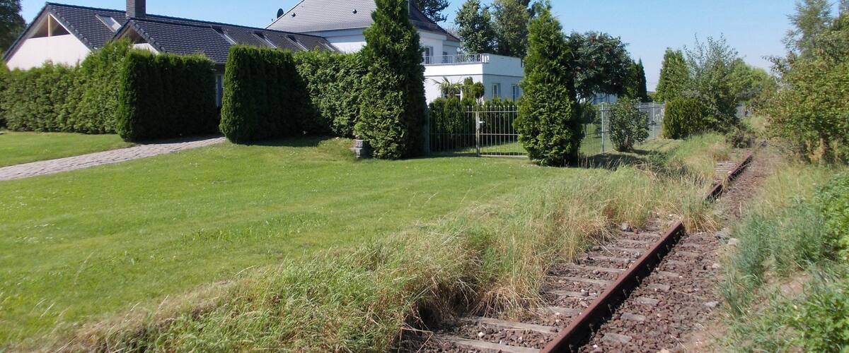A residential area with a house, a lawn, and a railway track.