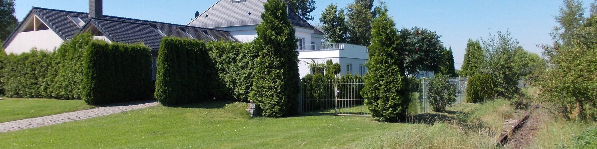 A residential area with a house, a lawn, and a railway track.