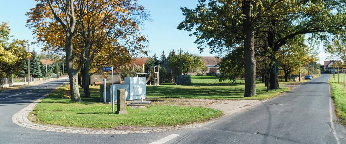 A suburban street lined with trees and a playground.