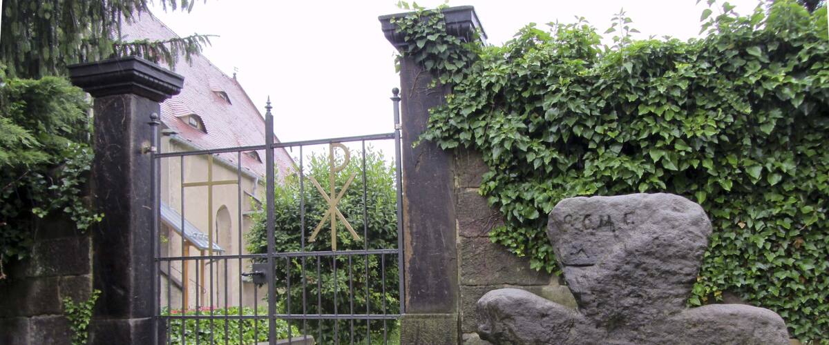 A stone sculpture of a bear, a metal gate, and a building with ivy.