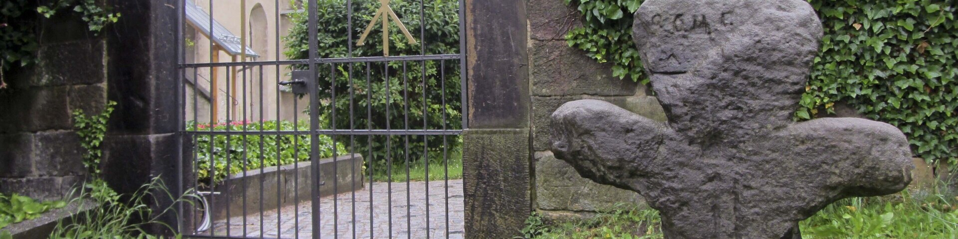 A stone sculpture of a bear, a metal gate, and a building with ivy.