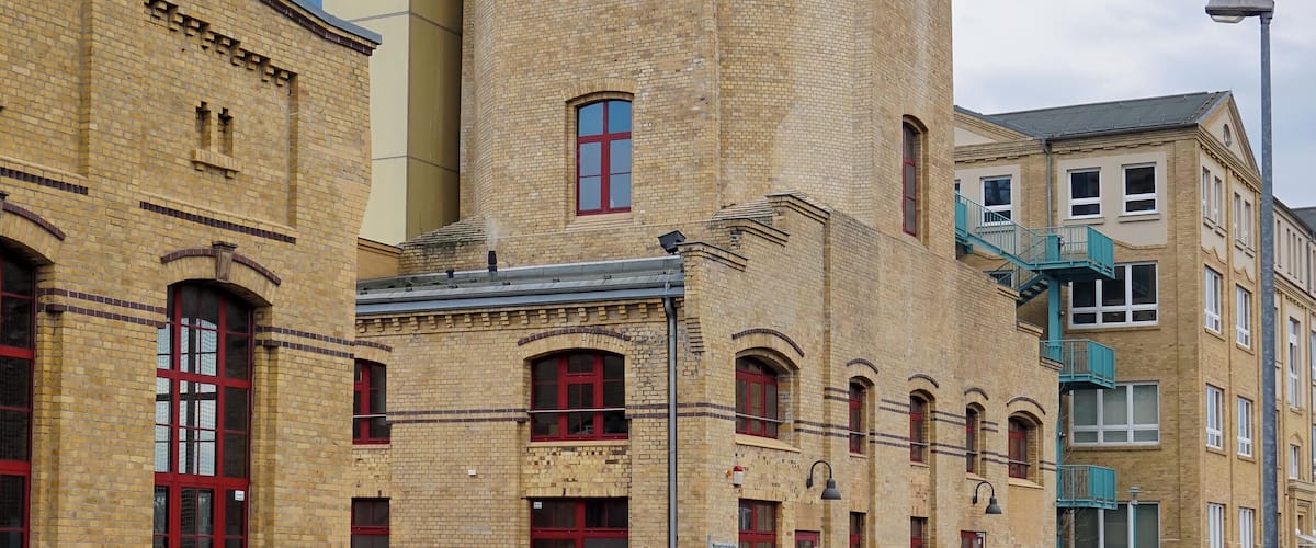 A historic tower with red windows and a modern building with a glass facade.