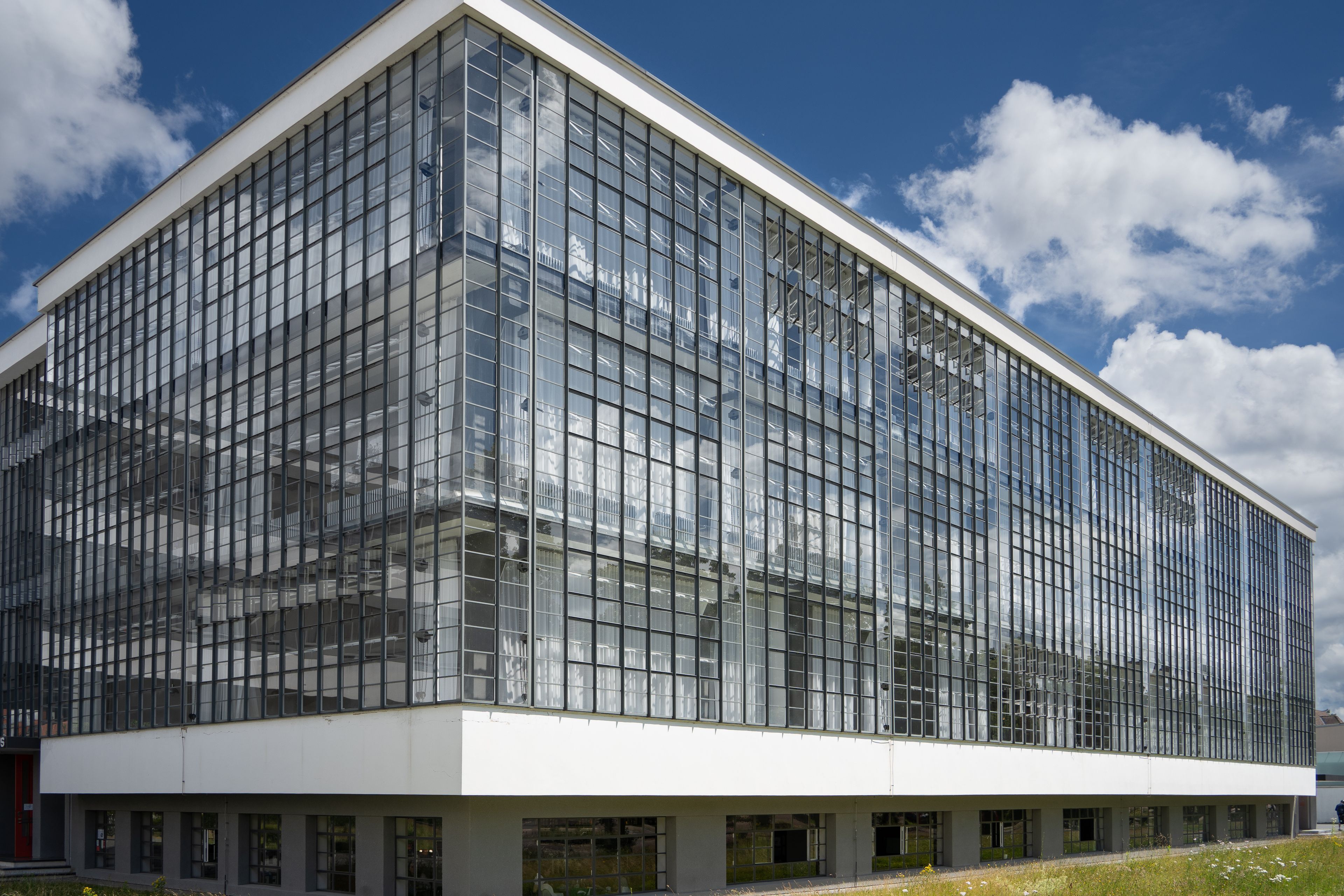 A modern glass building with a white facade and a flat roof.