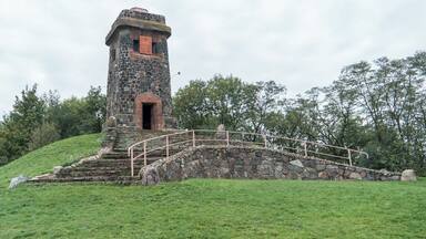 A stone tower with a red door and a metal bridge leading up to it.