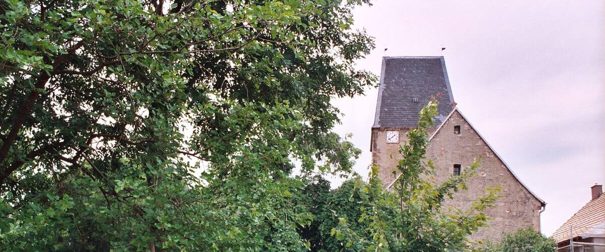 A rural landscape with a stone building, a statue, and a path leading to it.