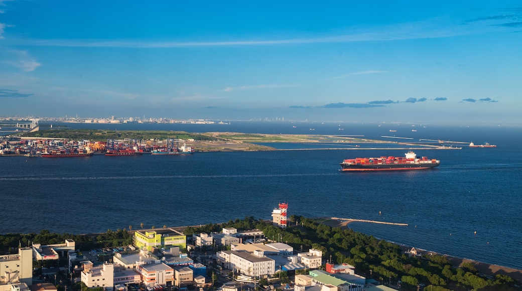 Un paisaje urbano costero con un gran carguero, un puente y una línea de horizonte de ciudad distante.