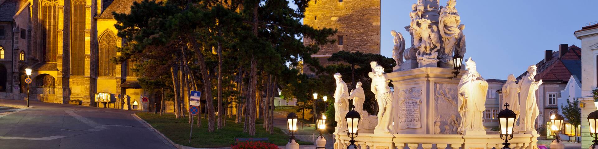 A historic church with a tall bell tower and a statue of a figure on a pedestal.