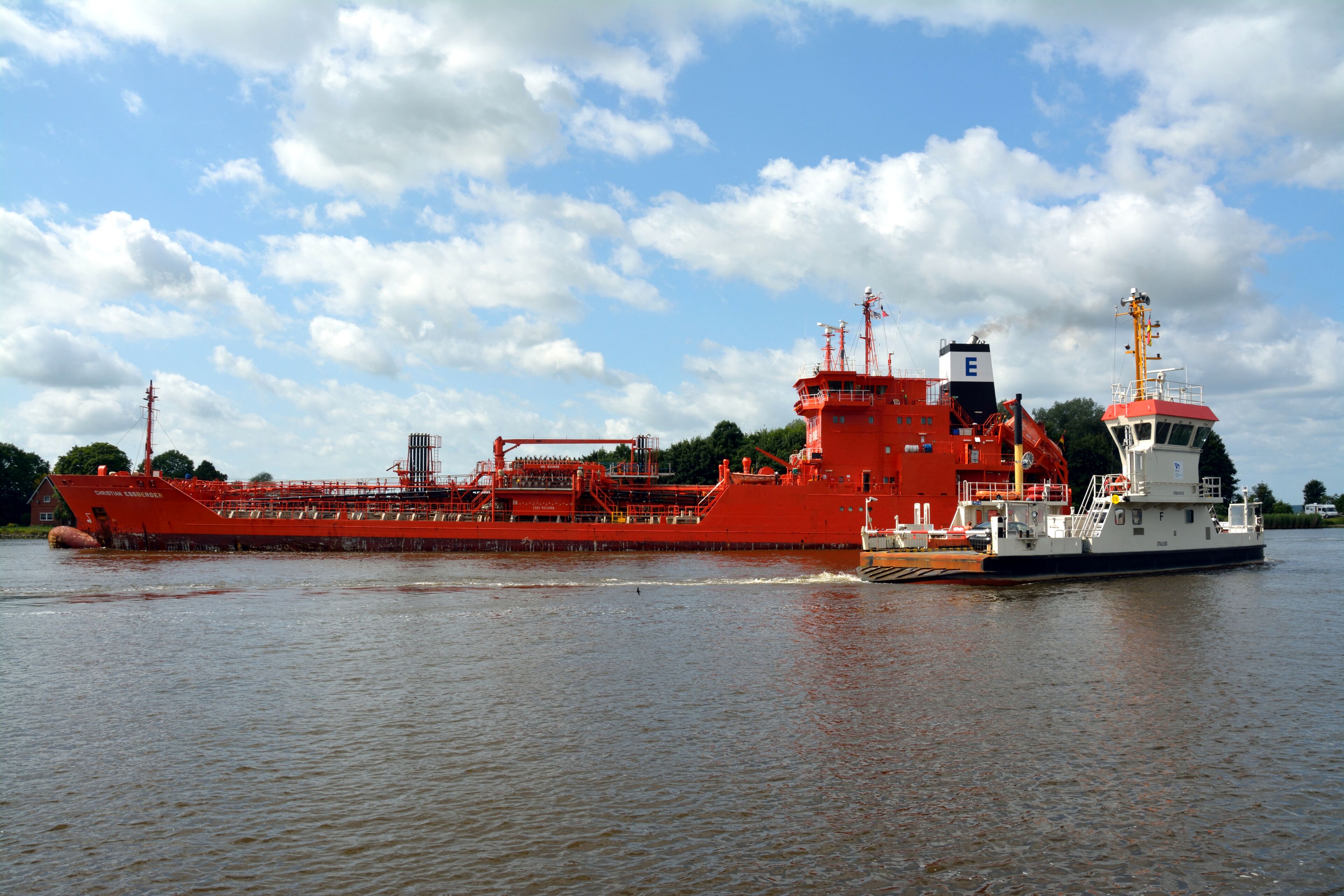 A large red cargo ship on a river.