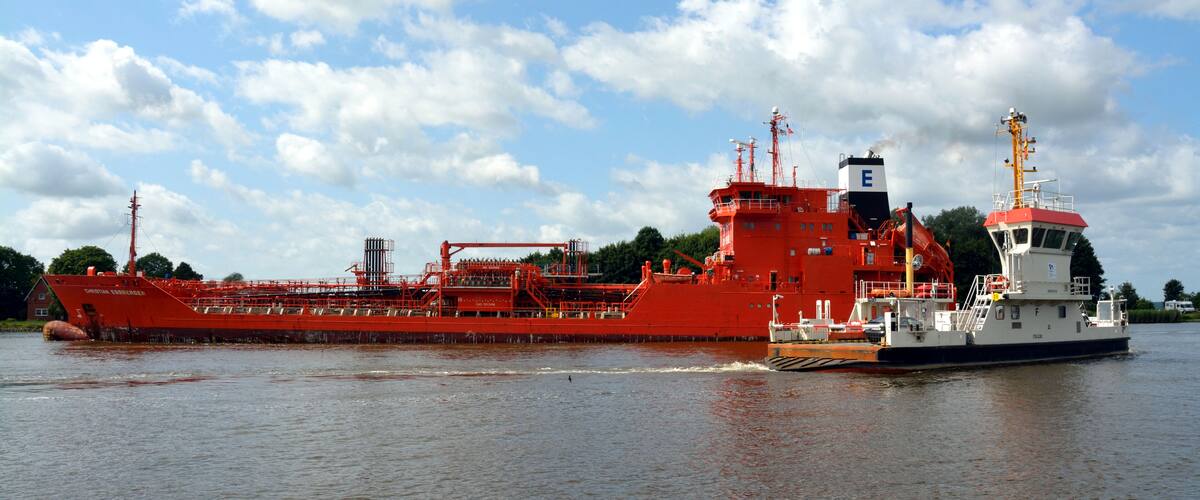 A large red cargo ship on a river.