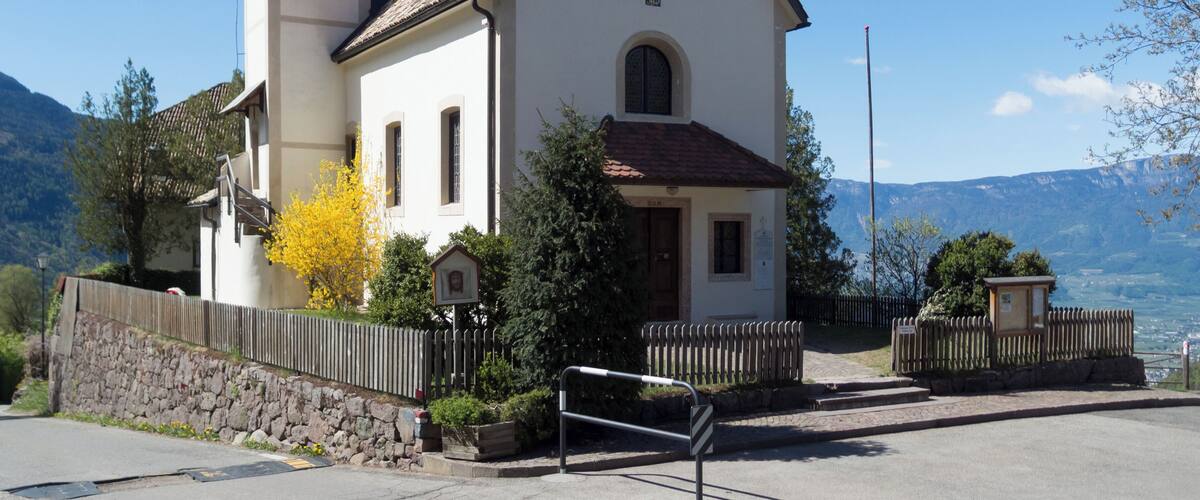 A church with a bell tower and a mountain backdrop.