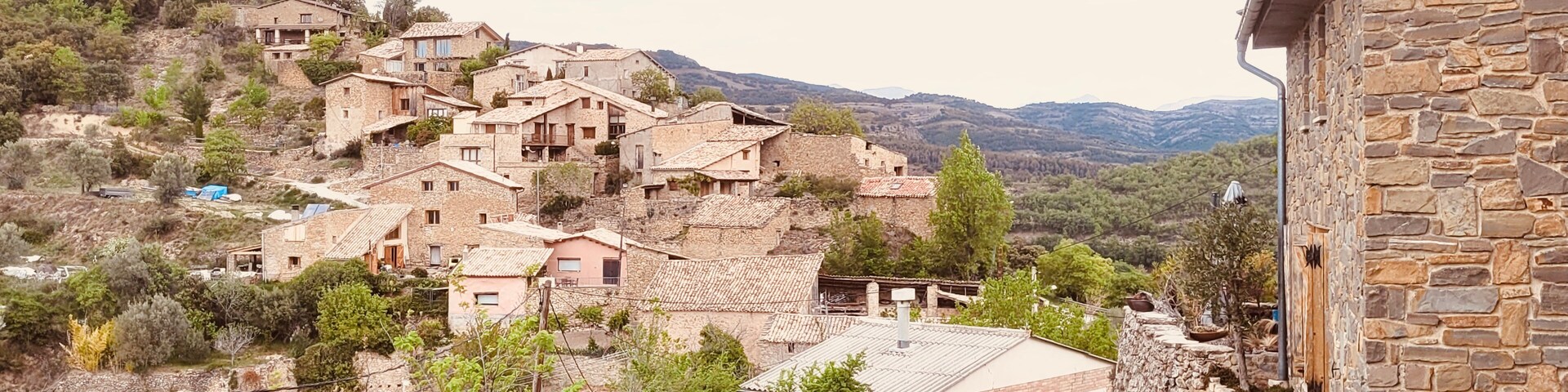 Un pueblo en una ladera con edificios de piedra y un sendero estrecho que lo atraviesa.