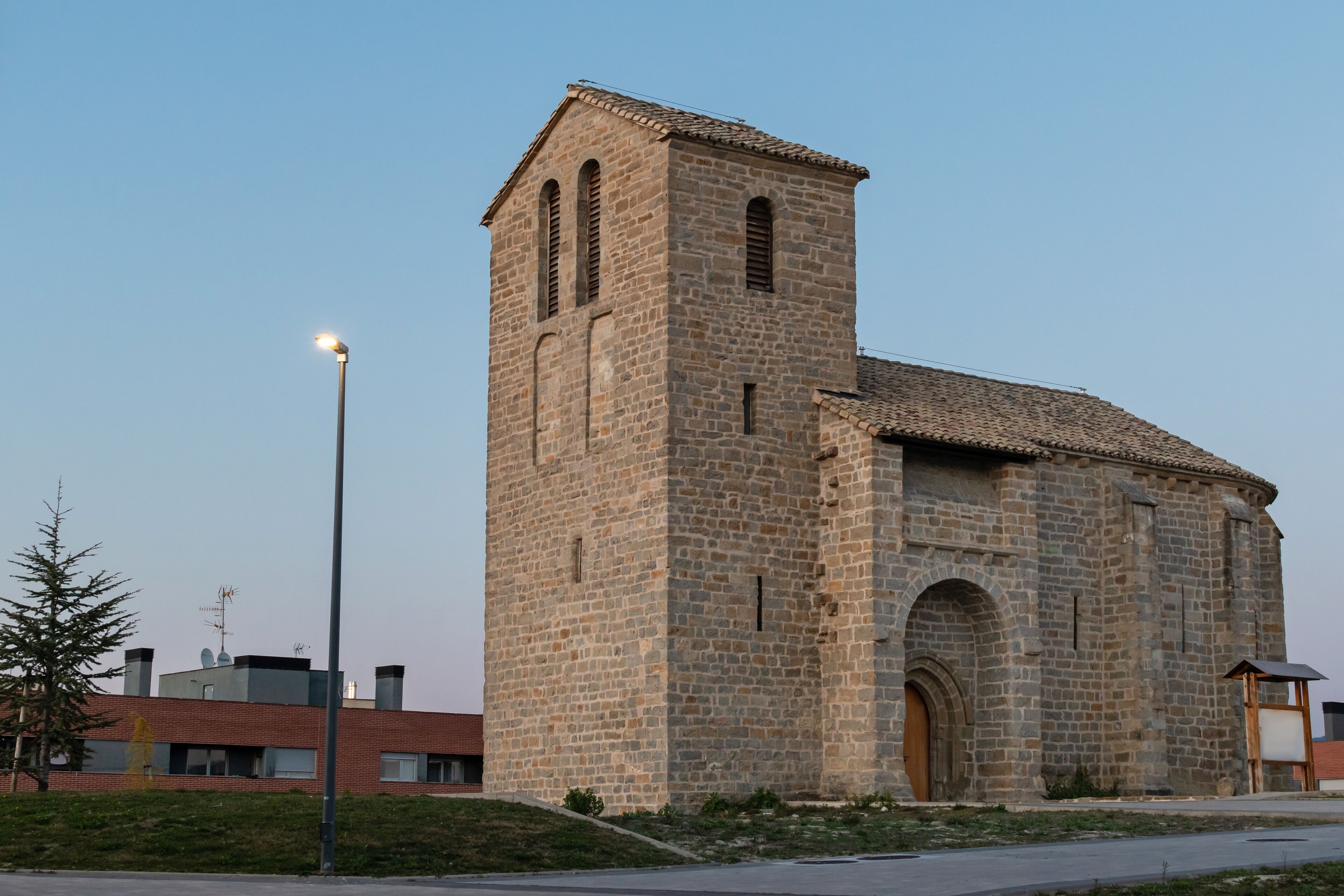 A stone church with a bell tower and a street lamp in front.