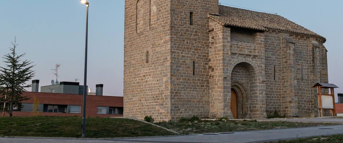 A stone church with a bell tower and a street lamp in front.