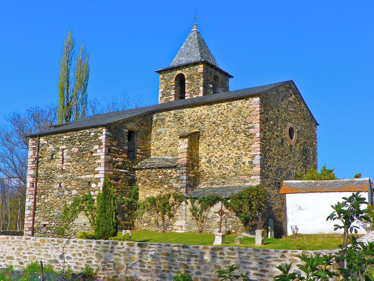 A stone church with a bell tower and ivy-covered walls.