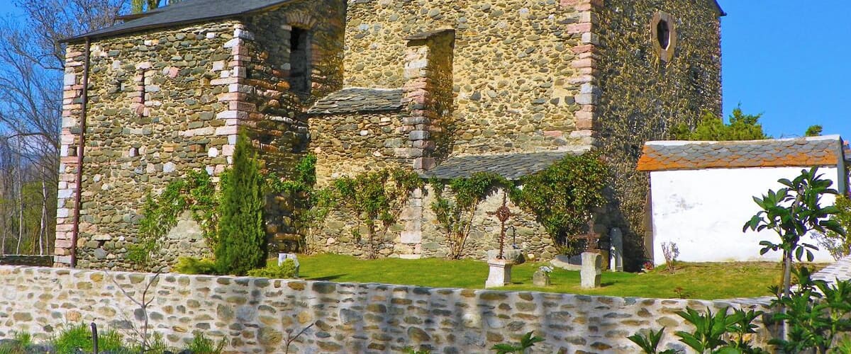 A stone church with a bell tower and ivy-covered walls.