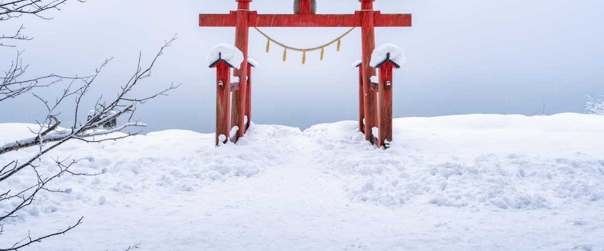 En snedækket torii-port i et vinterlandskab.