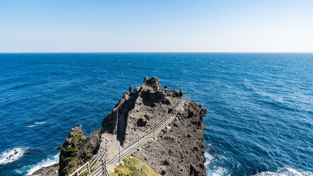 Une côte rocheuse avec un escalier métallique menant à une plateforme d’observation.