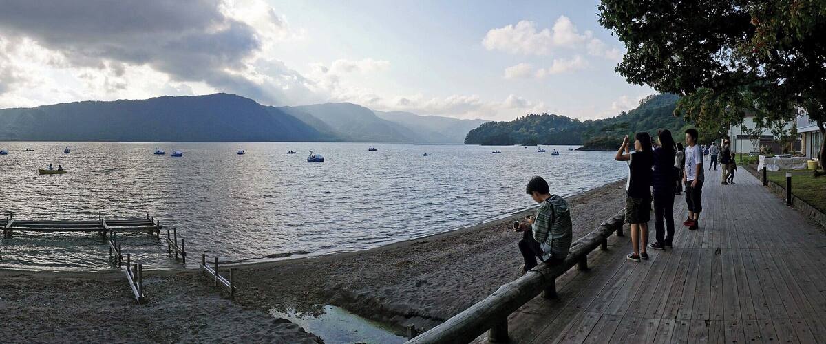 A lake with boats, a wooden dock, and mountains in the background.