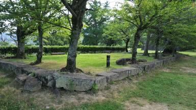 A park with stone walls, trees, and a grassy area.
