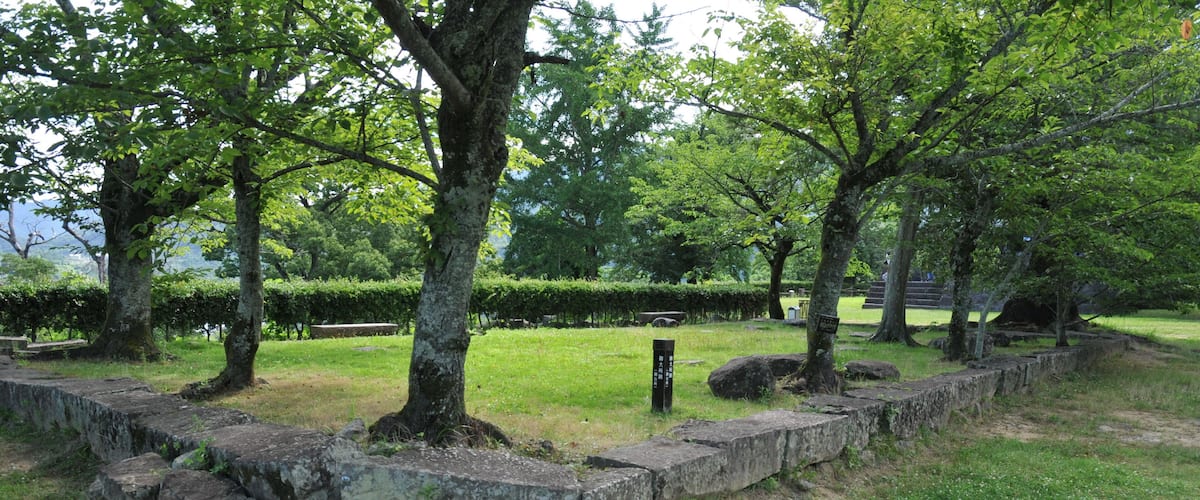 A park with stone walls, trees, and a grassy area.