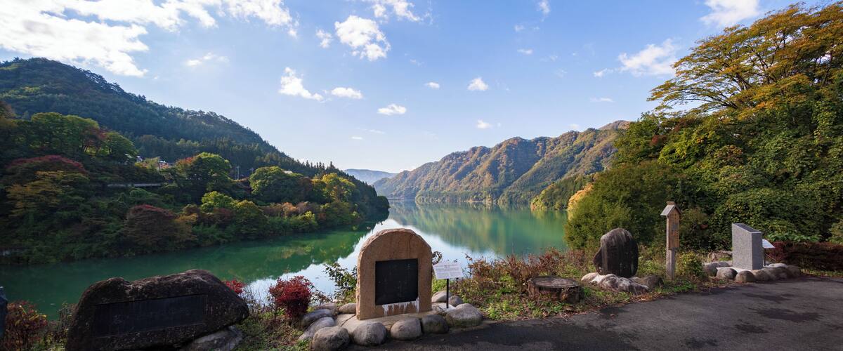 A serene lake surrounded by lush green hills and a clear sky.