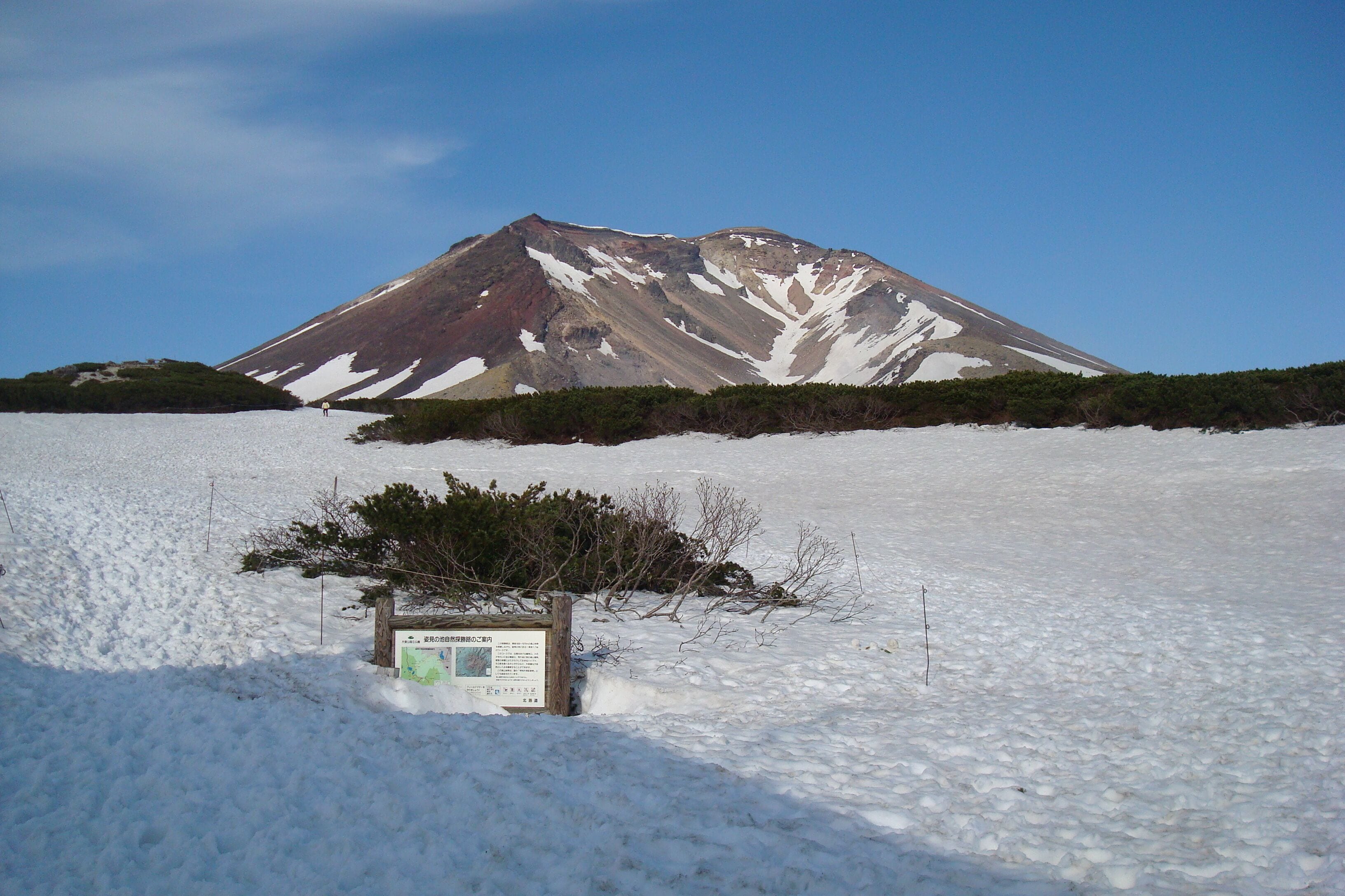 A snow-covered landscape with a mountain in the background and a sign in the foreground.