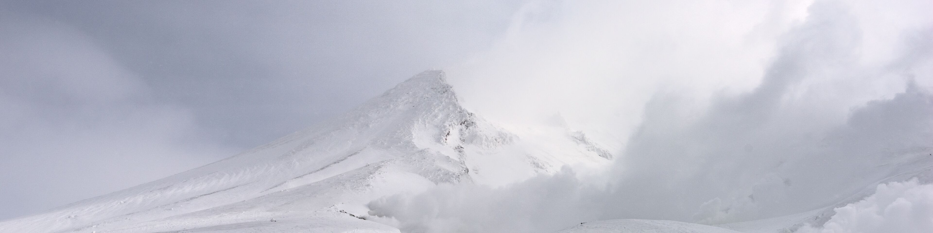 Una montaña nevada con un grupo de personas caminando sobre un terreno plano cubierto de nieve.