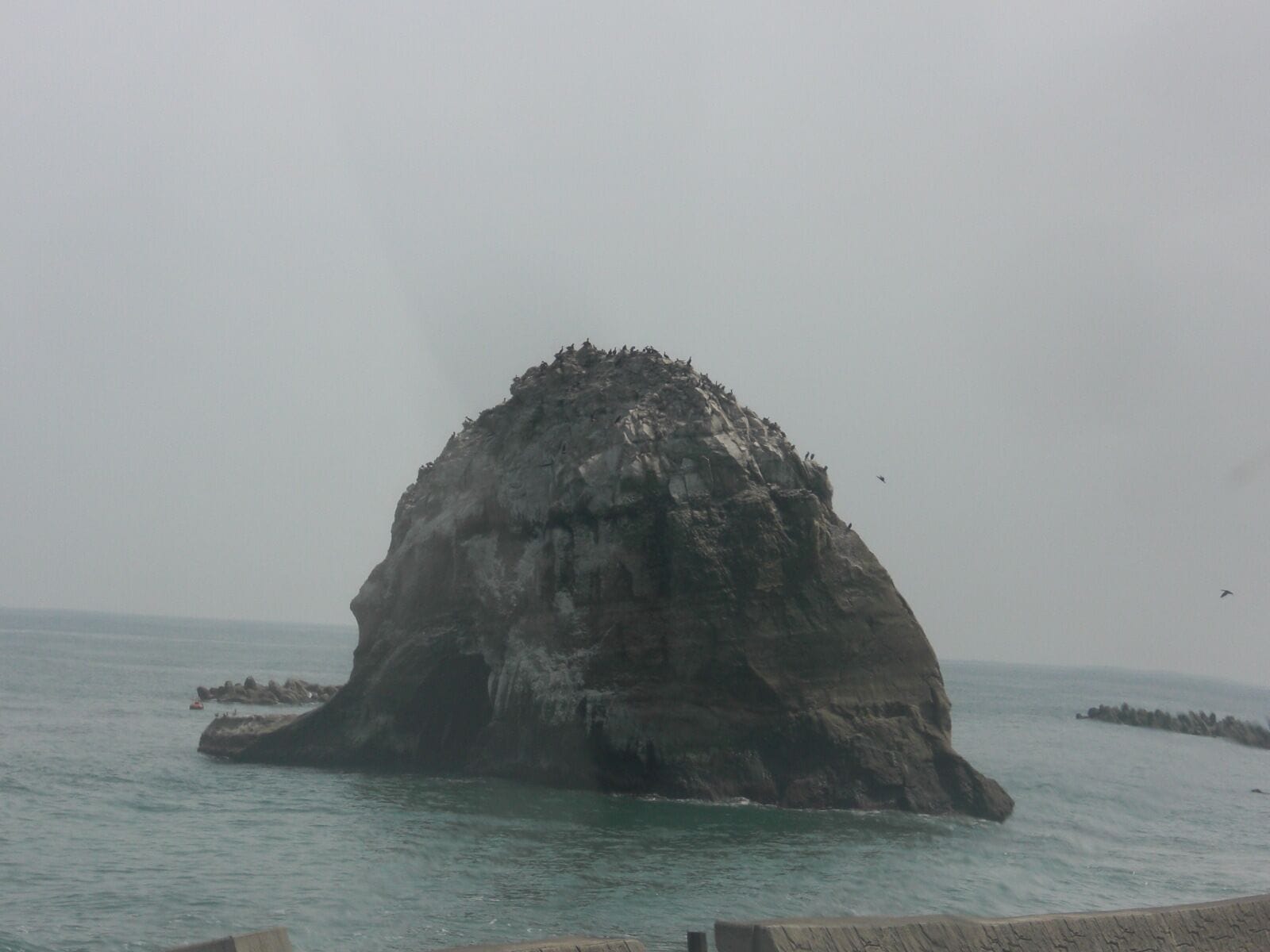 A large rock formation surrounded by water.