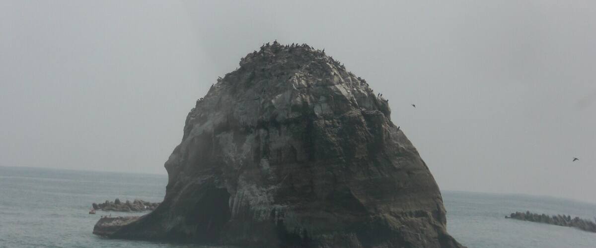 A large rock formation surrounded by water.