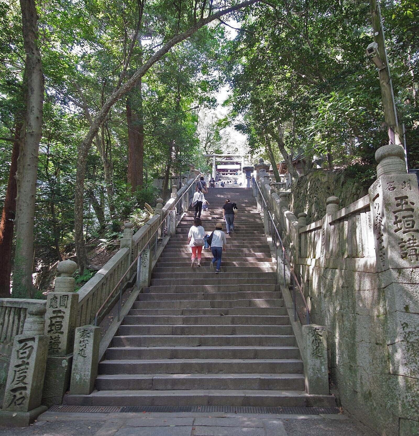 A stone staircase surrounded by trees leading to a temple entrance.