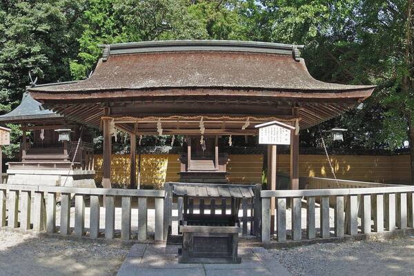 A traditional Japanese pavilion surrounded by stone lanterns and a wooden fence.