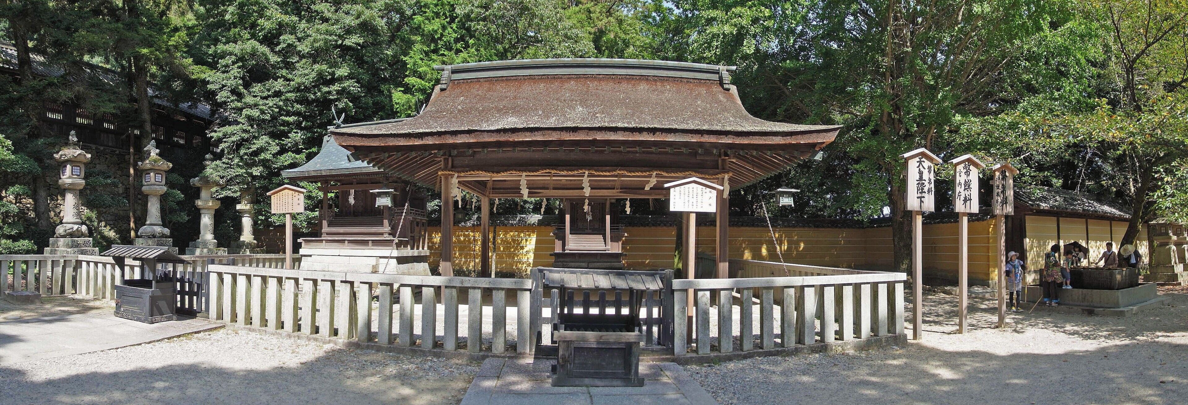 A traditional Japanese pavilion surrounded by stone lanterns and a wooden fence.