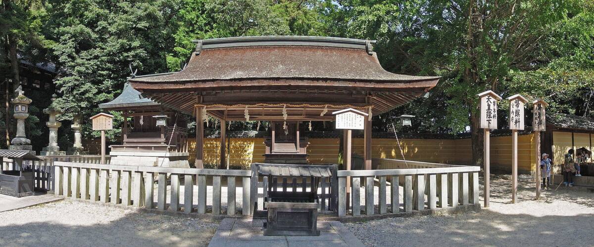 A traditional Japanese pavilion surrounded by stone lanterns and a wooden fence.
