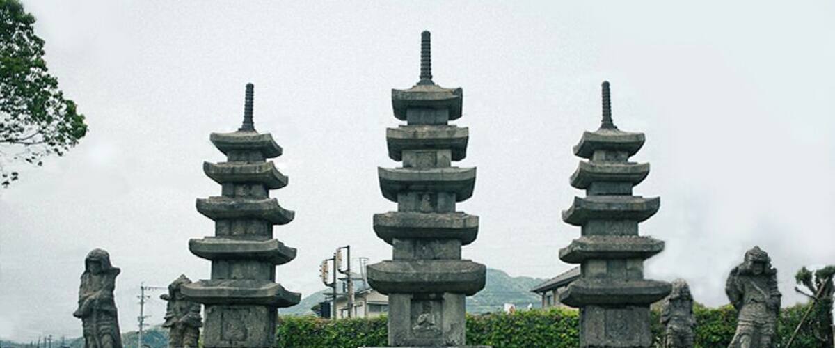 A traditional Japanese pagoda with multiple tiers, surrounded by stone statues and lush greenery.