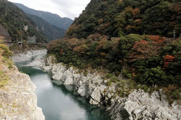 A river winding through a mountainous landscape with rocky banks and a boat in the water.