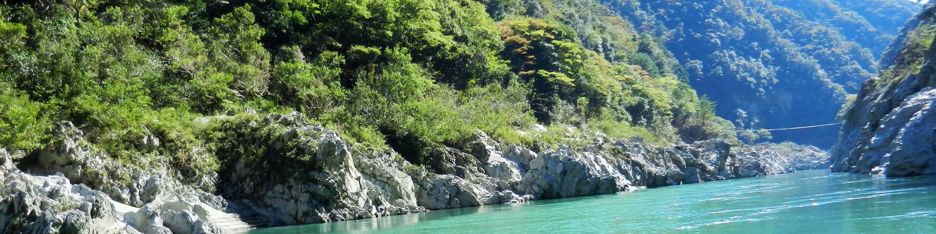 A turquoise river winding through a mountainous landscape with rocky shores and dense green foliage.