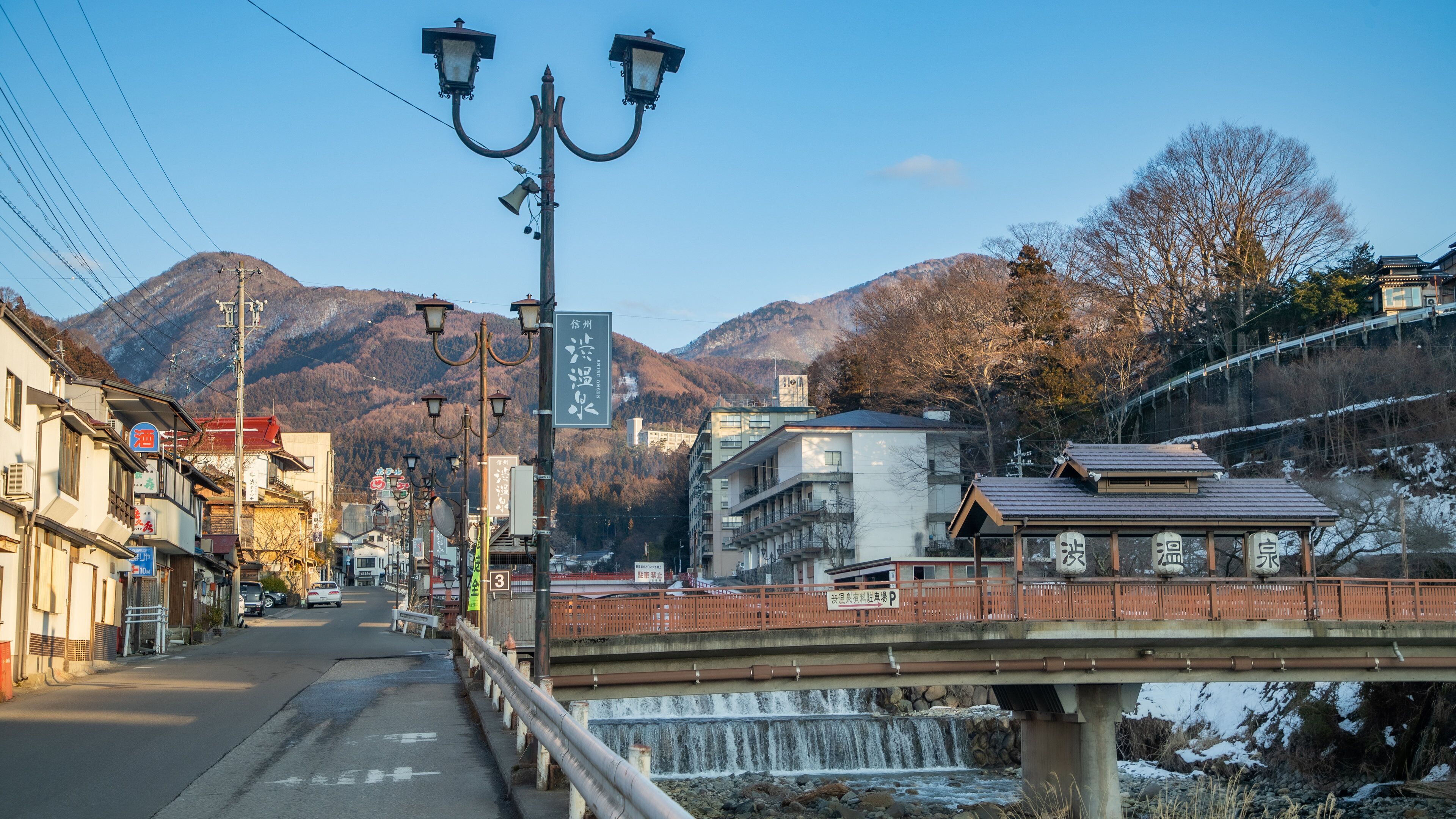 A bridge over a river with a mountainous backdrop.